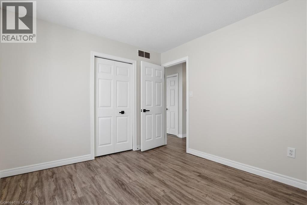 Spacious bedroom featuring warm wood-finish flooring, pristine white six-panel closet doors, and bright natural lighting from recessed ceiling fixtures - 43 Decaro Crescent, Cambridge, ON - Indoor Photo Showing Other Room