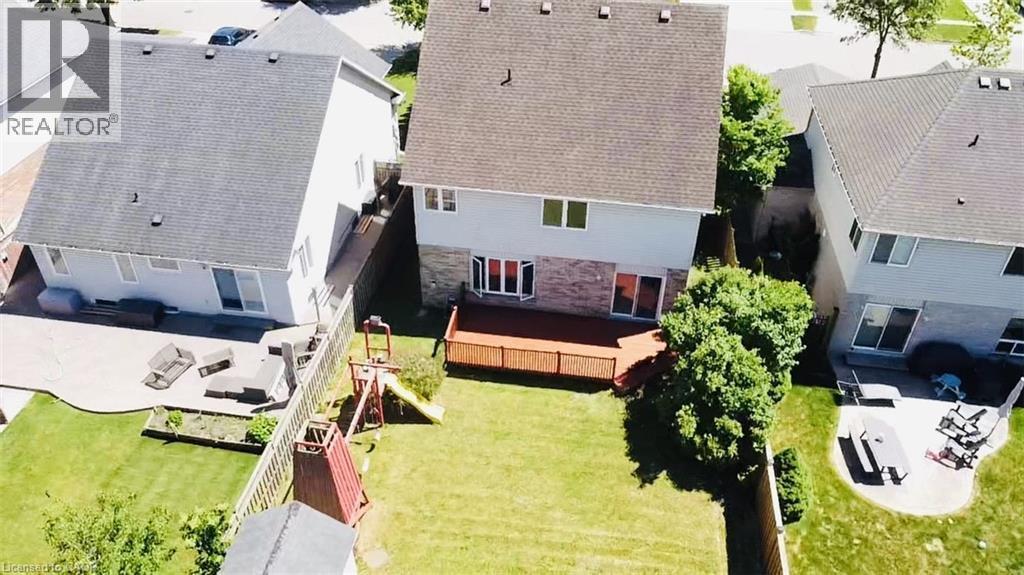 Expansive backyard featuring a manicured lawn, mature trees providing natural shade, a wooden deck with integrated seating area, and direct access from the home's rear elevation - 43 Decaro Crescent, Cambridge, ON - Outdoor