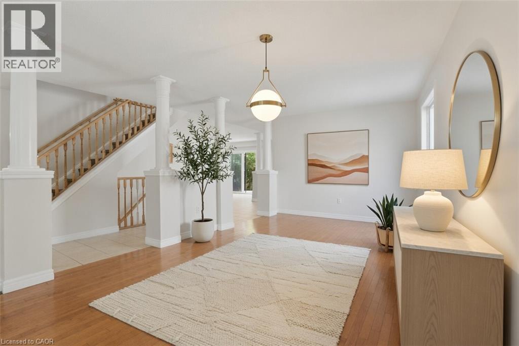 Welcoming foyer showcasing gleaming wood-finish flooring, a geometric area rug, and a wooden staircase with turned balusters - 43 Decaro Crescent, Cambridge, ON - Indoor Photo Showing Other Room