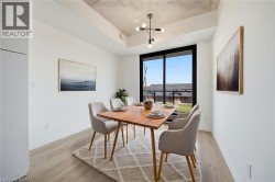 Modern dining area featuring a wood-finish table, upholstered chairs with tapered legs, wide-format windows with black frames flooding the space with natural light, light wood-finish flooring, and a g - 