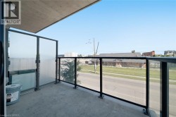 Modern elevated balcony featuring floor-to-ceiling glass railings, concrete flooring, and expansive sightlines overlooking the surrounding landscape - 