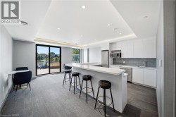 Modern kitchen with white cabinetry, stainless steel appliances, light countertops, and a gray subway tile backsplash - 