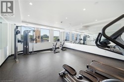 State-of-the-art fitness facility featuring premium cardio and strength training equipment, dark composite flooring, floor-to-ceiling windows with natural light, recessed ceiling lighting, and a spaci - 