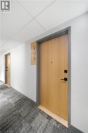 Light wood-finish entry door with matte black hardware - 