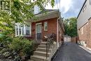 Brick exterior with white trim, front entrance with concrete steps and wrought iron railing, bay window, mature front landscaping, and a paved driveway leading to a detached garage - 23 Kipling Road, Hamilton, ON  - Outdoor With Exterior 