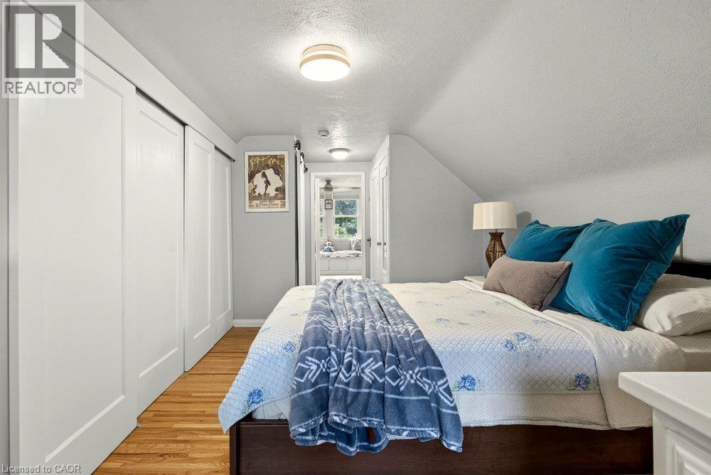 Wood-finish flooring, white sliding closet doors, ceiling-mounted lighting, and sloped ceiling - 23 Kipling Road, Hamilton, ON - Indoor Photo Showing Bedroom