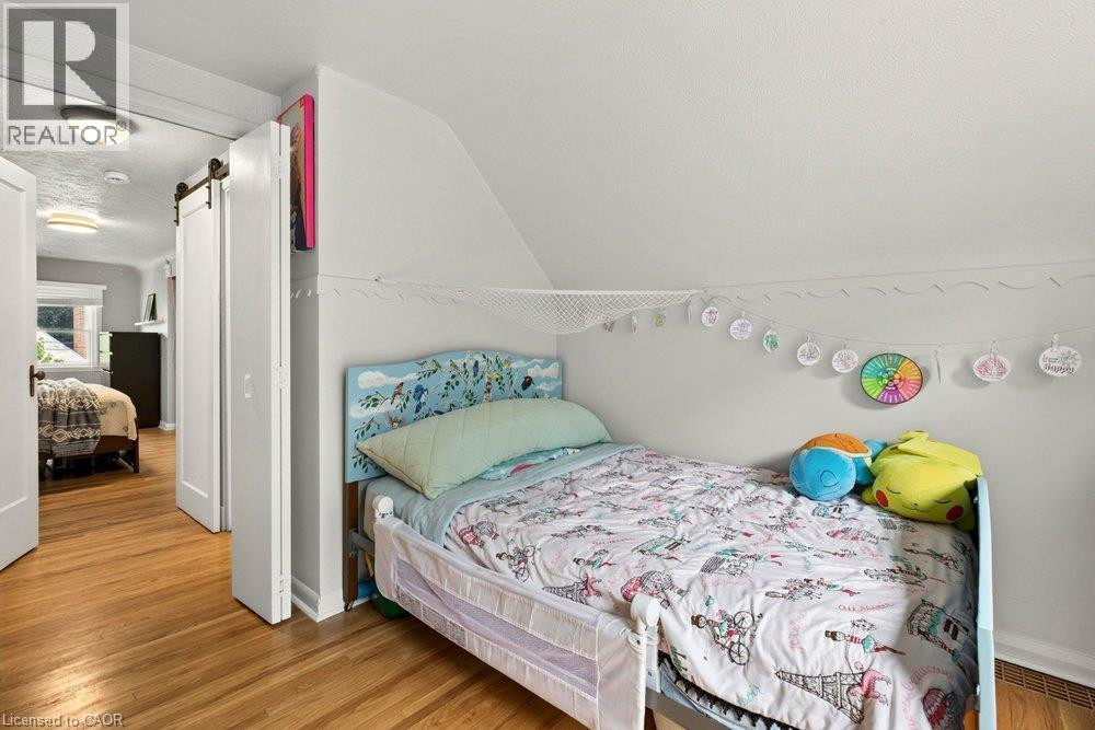 Bright bedroom featuring wood-finish flooring, sloped vaulted ceilings, and ample natural light from recessed fixtures - 23 Kipling Road, Hamilton, ON - Indoor Photo Showing Bedroom