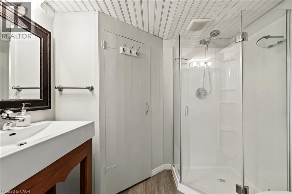 Modern primary bathroom featuring a floating vanity with integrated sink and ample countertop space, polished chrome fixtures, framed mirror with integrated lighting, and a walk-in shower enclosure wi - 23 Kipling Road, Hamilton, ON - Indoor Photo Showing Bathroom