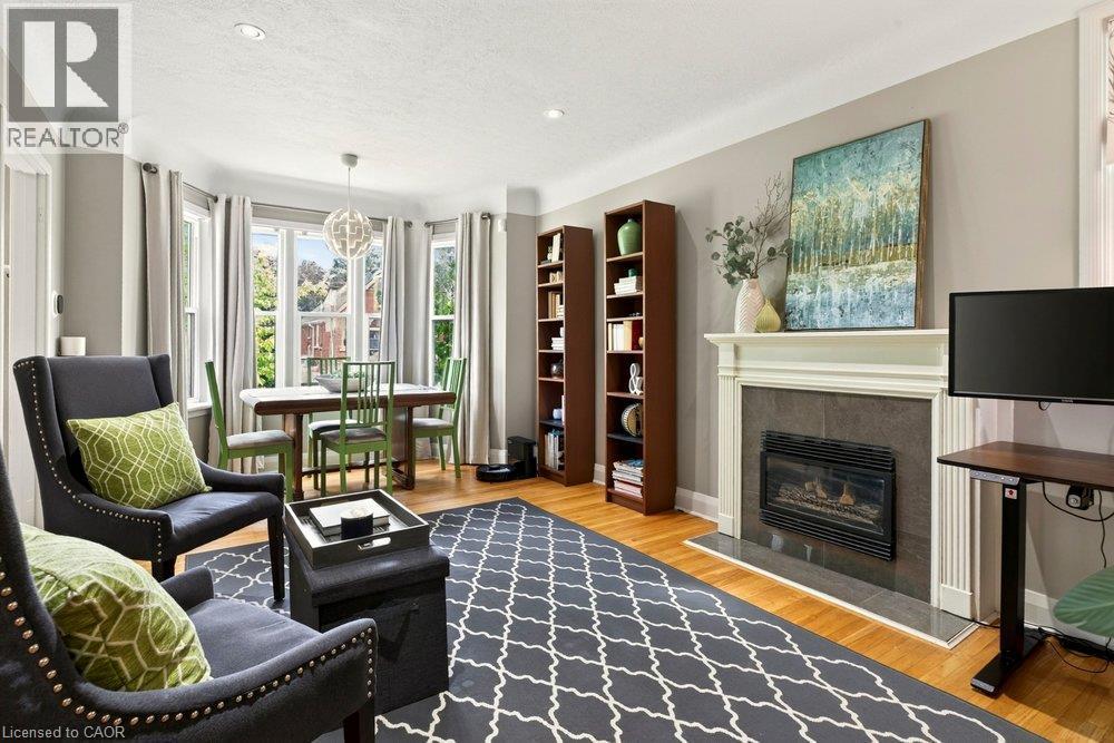 Hardwood flooring, fireplace with stone surround and white mantle, recessed lighting, and bay windows - 23 Kipling Road, Hamilton, ON - Indoor Photo Showing Living Room With Fireplace