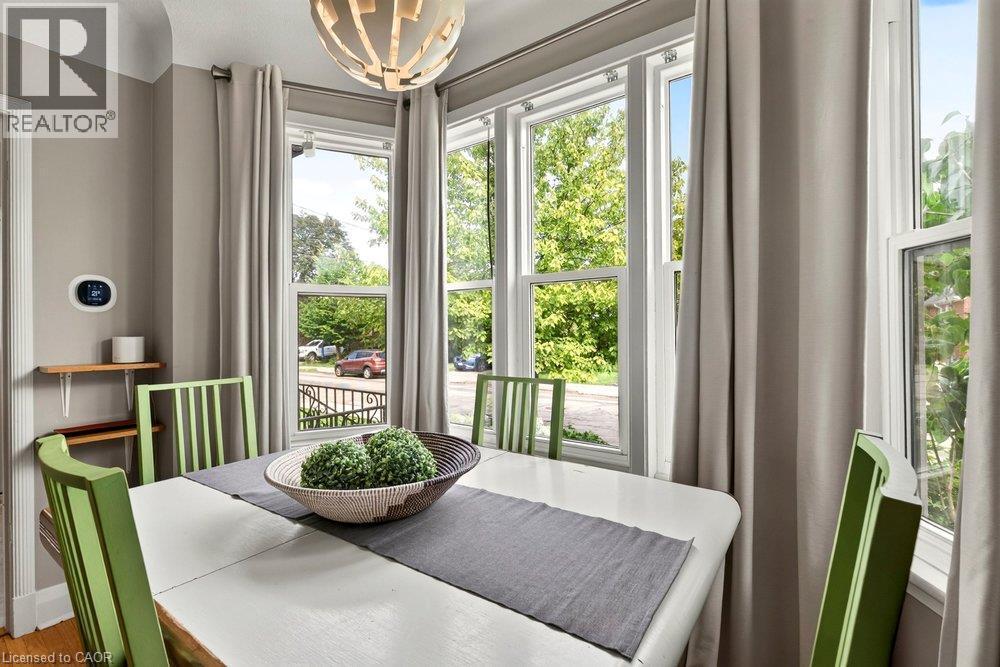 Bay window with white trim, contemporary light fixture, hardwood flooring, and light gray wall paint - 23 Kipling Road, Hamilton, ON - Indoor Photo Showing Dining Room