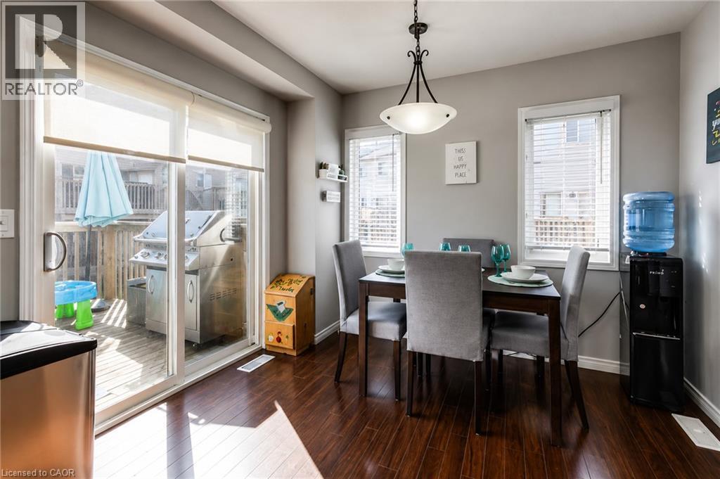 Dining area featuring wood-finish flooring, a contemporary chandelier, and a sliding glass door opening to a deck - 750 Lawrence Street Unit# 86, Cambridge, ON - Indoor Photo Showing Dining Room