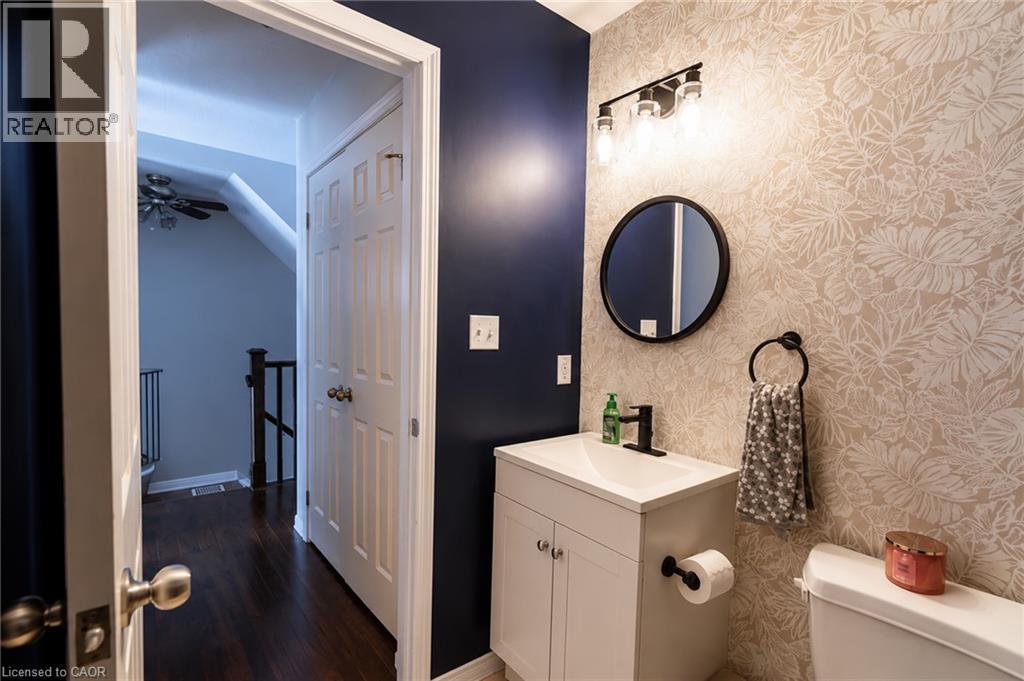 Contemporary bathroom featuring a white vanity with ample storage, polished chrome hardware, and a circular mirror with integrated lighting - 750 Lawrence Street Unit# 86, Cambridge, ON - Indoor Photo Showing Bathroom