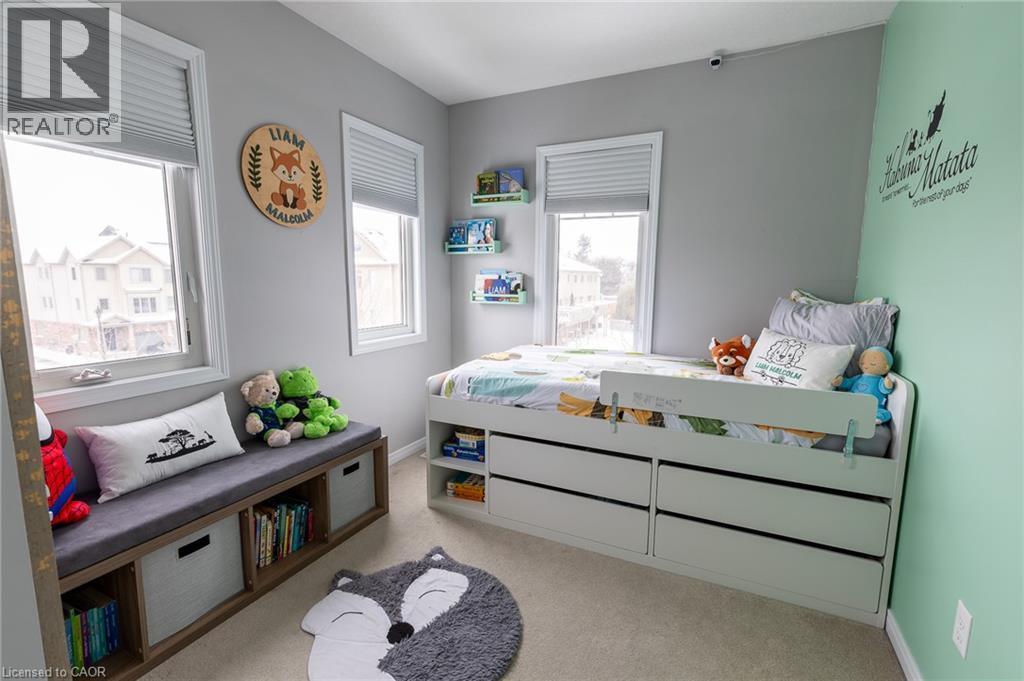 Bright, light-filled bedroom featuring multiple windows with cellular shades, soft mint accent wall, built-in storage bed with integrated drawers, and a wood-finish storage bench with cushioned seatin - 750 Lawrence Street Unit# 86, Cambridge, ON - Indoor Photo Showing Bedroom