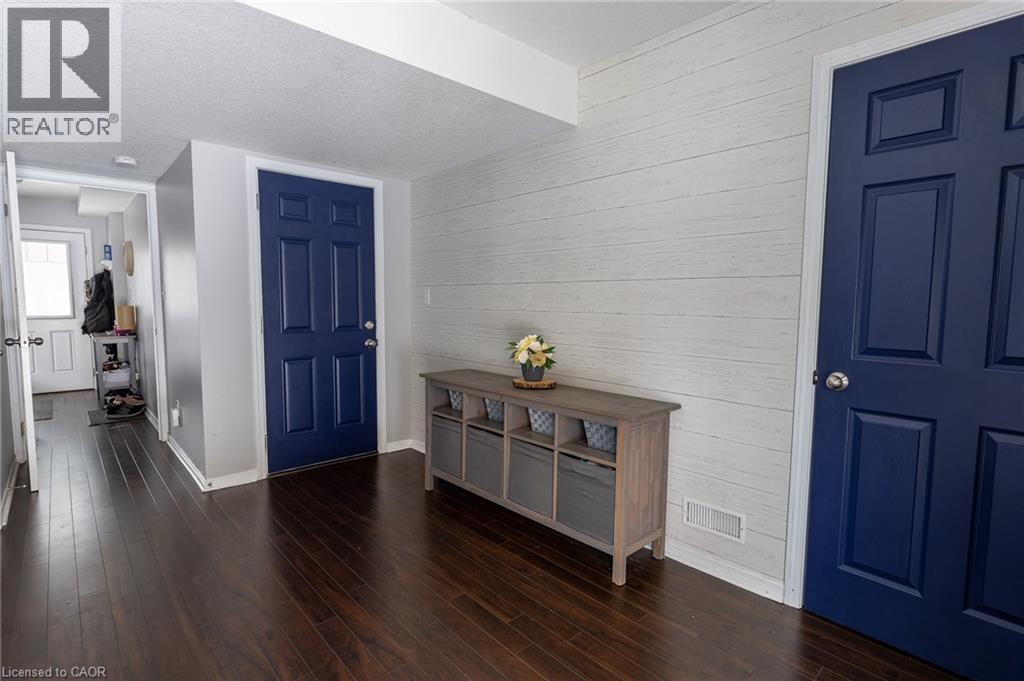 Dark wood-finish flooring, two deep blue paneled doors, and a decorative shiplap accent wall - 750 Lawrence Street Unit# 86, Cambridge, ON - Indoor Photo Showing Other Room