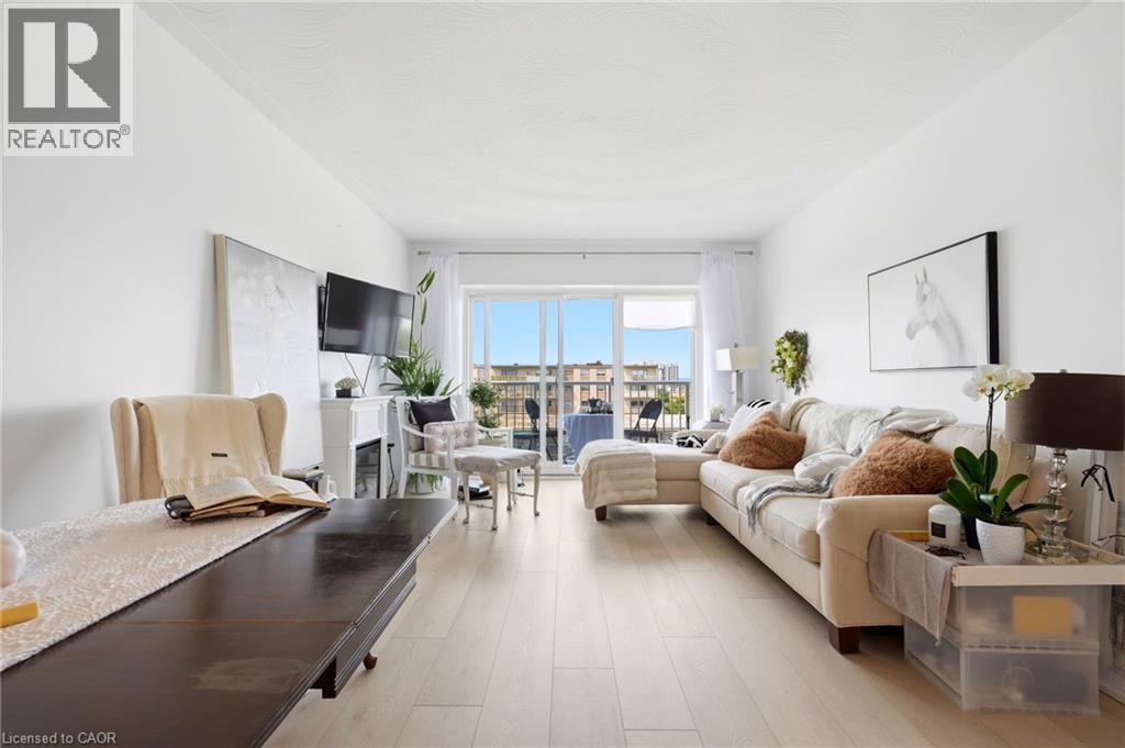 Light wood-finish flooring, white walls, and glass sliding doors leading to an outdoor balcony - 8 Woodman Drive S Unit# 708, Hamilton, ON - Indoor Photo Showing Living Room