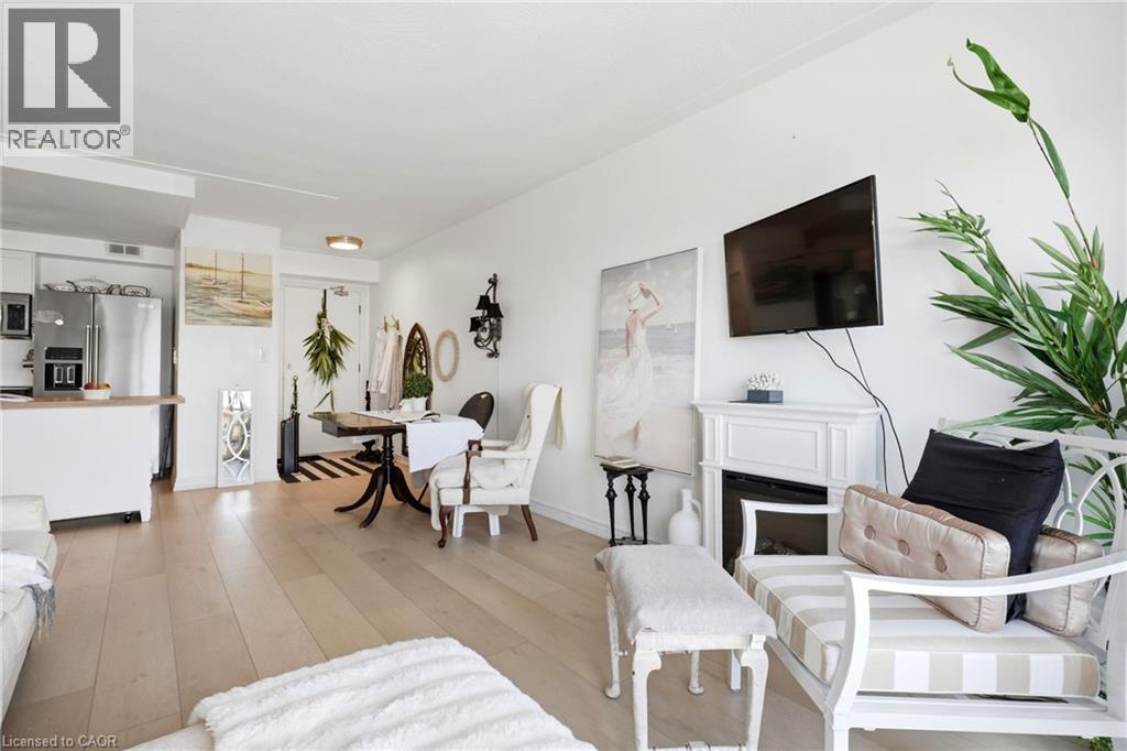 Light wood-finish flooring throughout, white walls, and a fireplace with a white mantel - 8 Woodman Drive S Unit# 708, Hamilton, ON - Indoor