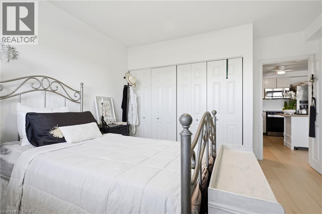 White painted walls, wood-finish flooring, and white bi-fold closet doors - 8 Woodman Drive S Unit# 708, Hamilton, ON - Indoor Photo Showing Bedroom