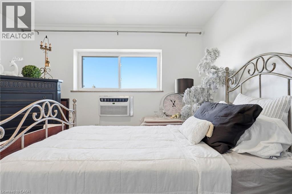 White painted walls with a window and a wall-mounted air conditioning unit - 8 Woodman Drive S Unit# 708, Hamilton, ON - Indoor Photo Showing Bedroom