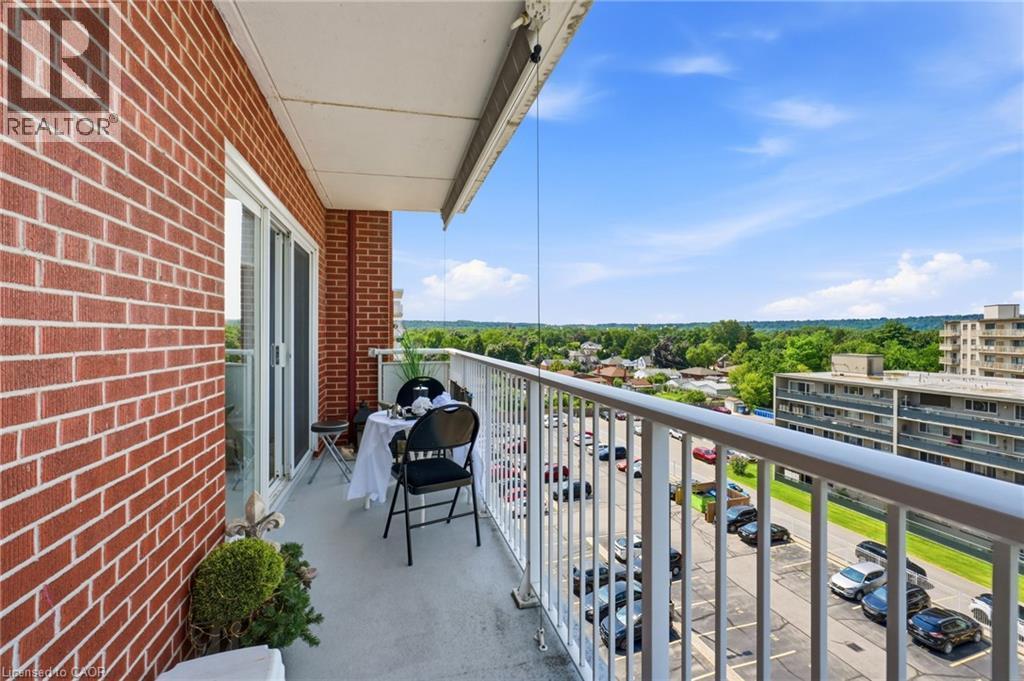 Private balcony with a sliding glass door, white railing, and red brick exterior - 8 Woodman Drive S Unit# 708, Hamilton, ON - Outdoor With Balcony With Exterior