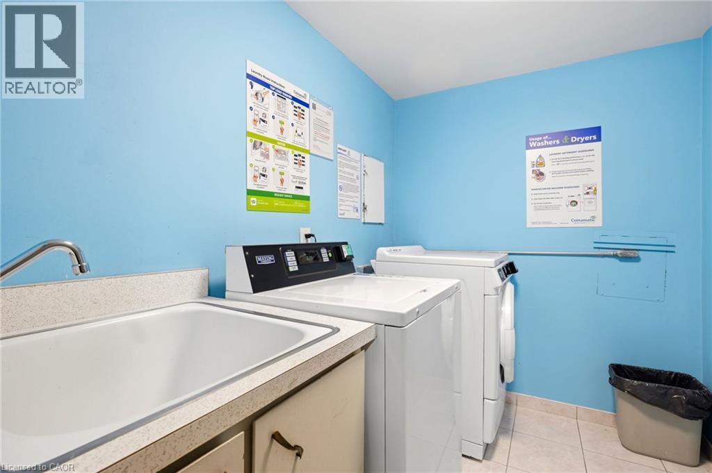 White ceramic utility sink with a chrome-finish faucet, accompanied by a washing machine and a dryer - 8 Woodman Drive S Unit# 708, Hamilton, ON - Indoor Photo Showing Laundry Room