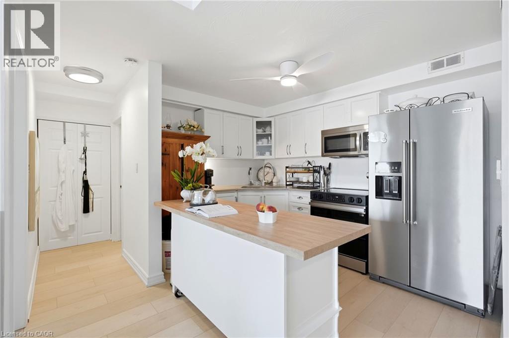 Kitchen featuring white cabinetry, stainless steel appliances, a wood-finish island with wheels, and wood-finish flooring - 8 Woodman Drive S Unit# 708, Hamilton, ON - Indoor Photo Showing Kitchen With Stainless Steel Kitchen