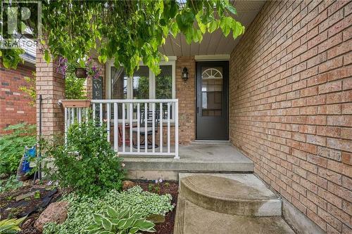 Brick exterior with a covered porch, white railing, and an arched glass door - 817 Acadia Drive, Hamilton, ON - Outdoor With Deck Patio Veranda