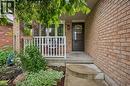 Brick exterior with a covered porch, white railing, and an arched glass door - 817 Acadia Drive, Hamilton, ON  - Outdoor With Deck Patio Veranda 