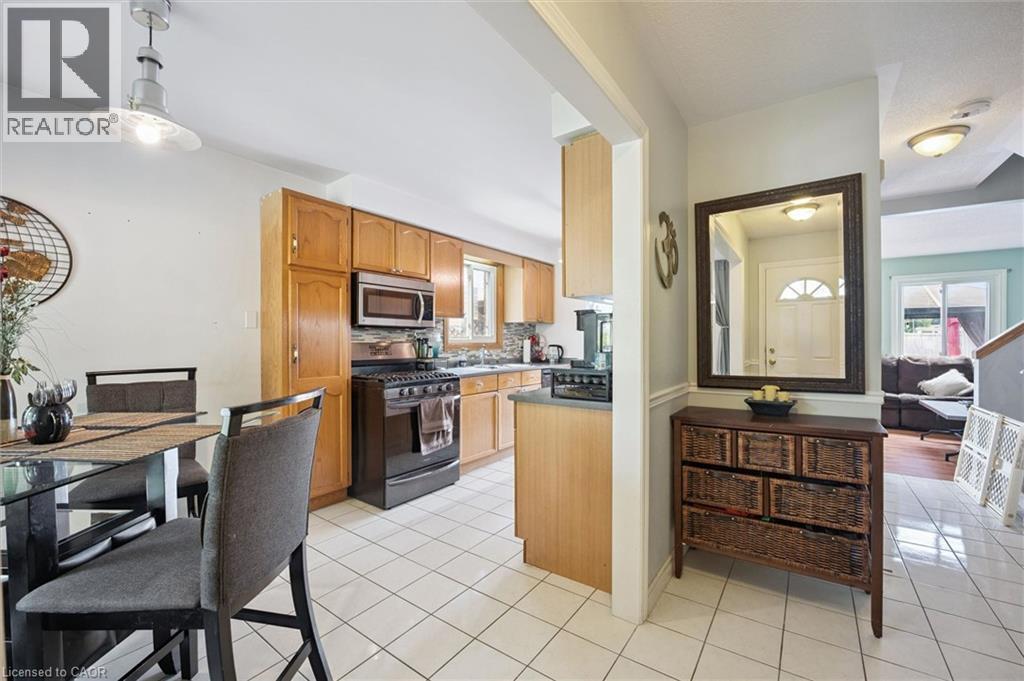 Kitchen featuring wood-finish cabinetry, stainless steel microwave, black gas range, and tile flooring - 817 Acadia Drive, Hamilton, ON - Indoor Photo Showing Kitchen