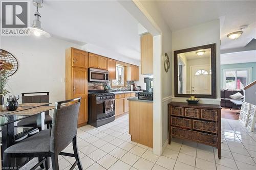 Kitchen featuring wood-finish cabinetry, stainless steel microwave, black gas range, and tile flooring - 817 Acadia Drive, Hamilton, ON - Indoor Photo Showing Kitchen