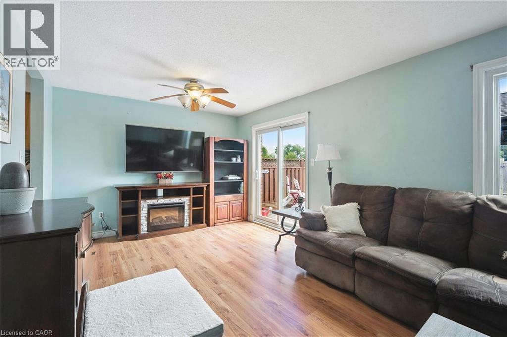 Recessed lighting, wood-finish flooring, ceiling fan, built-in media console with fireplace, and sliding glass door to outdoor area - 817 Acadia Drive, Hamilton, ON - Indoor Photo Showing Living Room