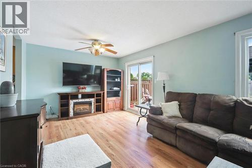 Recessed lighting, wood-finish flooring, ceiling fan, built-in media console with fireplace, and sliding glass door to outdoor area - 817 Acadia Drive, Hamilton, ON - Indoor Photo Showing Living Room