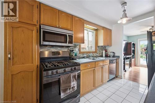 Kitchen featuring wood-finish cabinetry, stainless steel appliances, tile backsplash, and a double basin sink - 817 Acadia Drive, Hamilton, ON - Indoor Photo Showing Kitchen With Double Sink