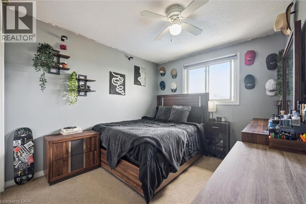 Neutral wall paint, ceiling fan with integrated lighting, wood-finish flooring, and a large window providing natural illumination - 817 Acadia Drive, Hamilton, ON - Indoor Photo Showing Bedroom