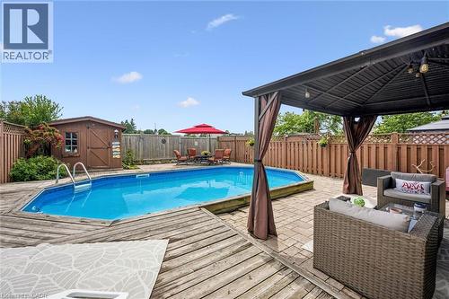 Outdoor swimming pool with surrounding wooden decking and paver patio - 817 Acadia Drive, Hamilton, ON - Outdoor With Above Ground Pool With Deck Patio Veranda