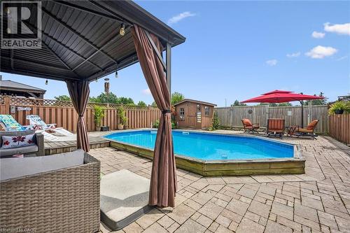 Patio featuring a swimming pool with a surrounding wood deck, a covered gazebo, and a storage shed - 817 Acadia Drive, Hamilton, ON - Outdoor With Deck Patio Veranda