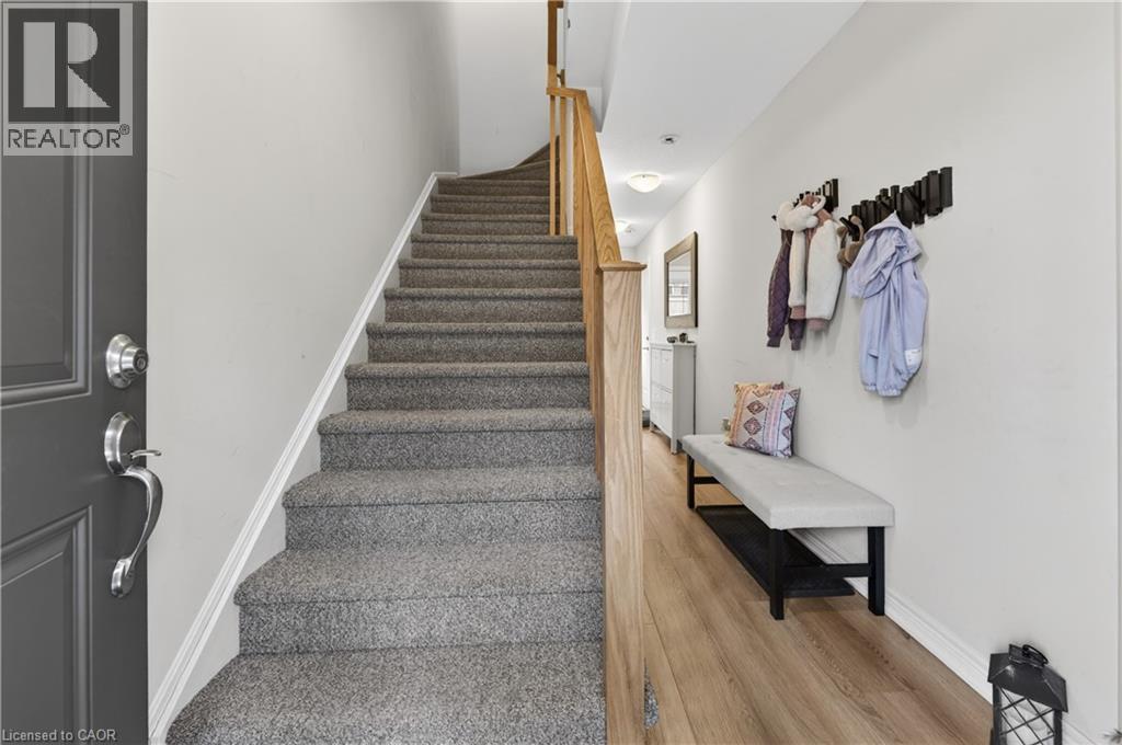 Entryway featuring wood-finish flooring, a carpeted staircase with a wood handrail, and an integrated wall-mounted coat rack - 19 Picardy Drive Unit# 13, Hamilton, ON - Indoor Photo Showing Other Room