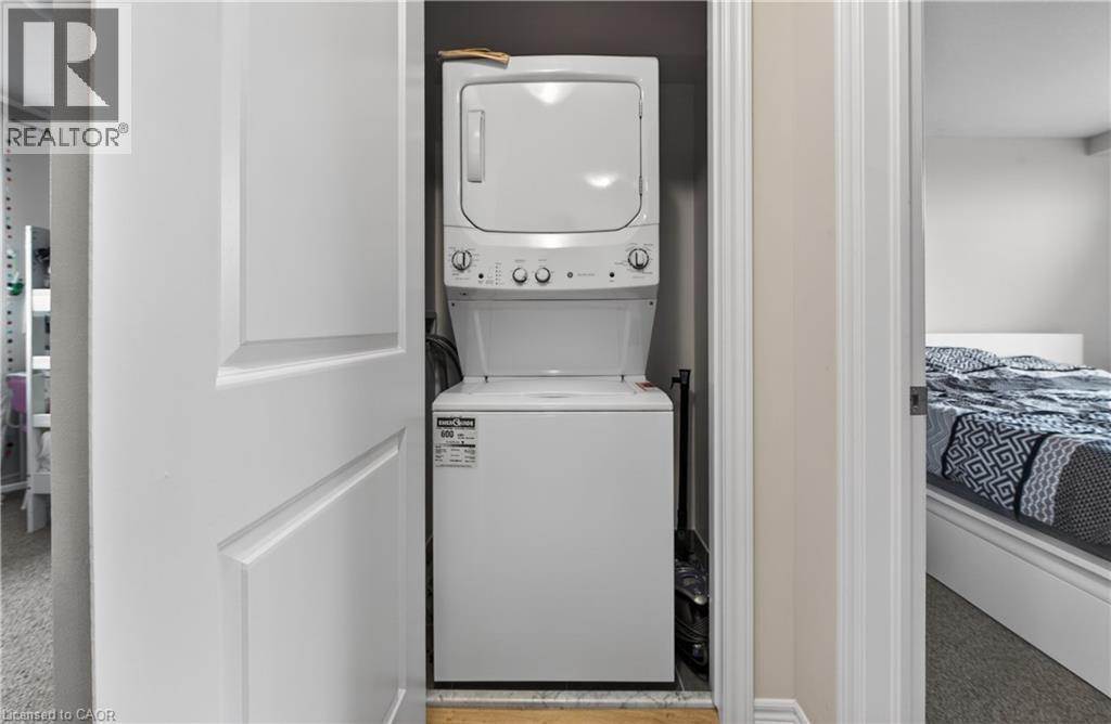 White stackable washer and dryer unit within a dedicated closet - 19 Picardy Drive Unit# 13, Hamilton, ON - Indoor Photo Showing Laundry Room