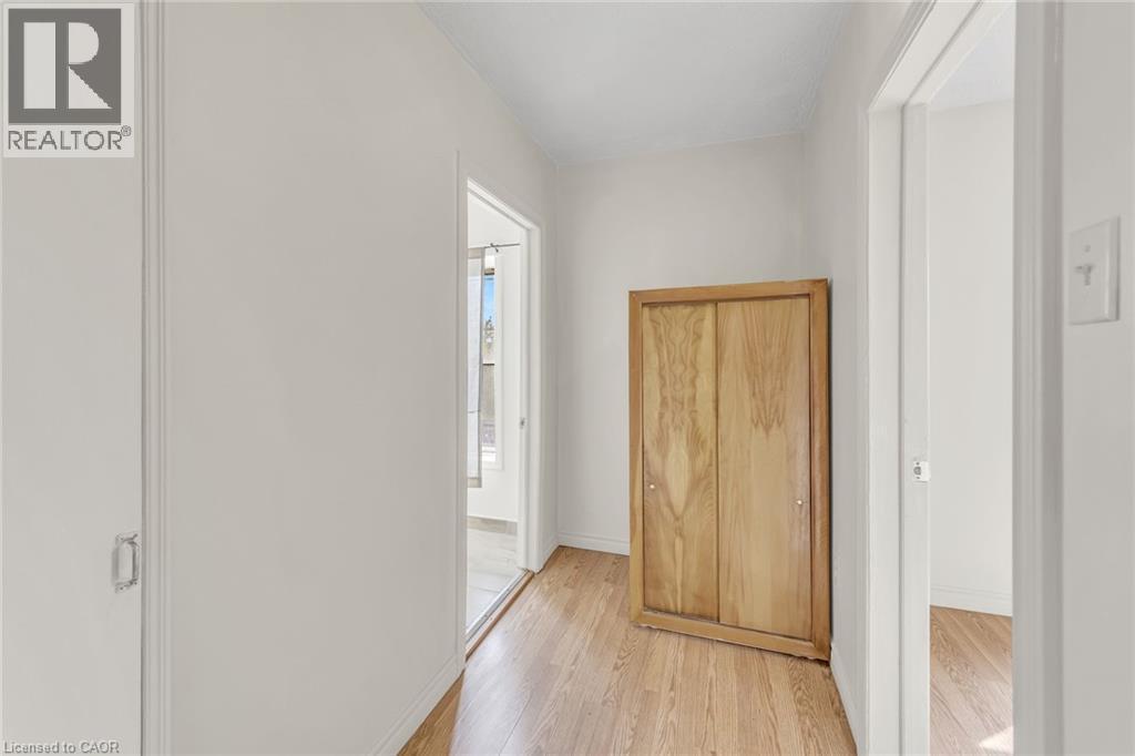 Wood-finish flooring throughout, white painted walls, and a built-in wooden cabinet with sliding doors - 1367 Cannon Street E, Hamilton, ON - Indoor Photo Showing Other Room