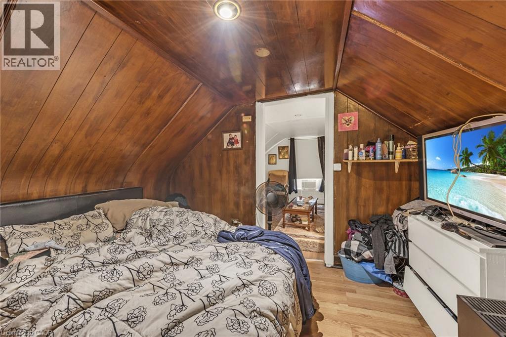 Wood-paneled walls and ceiling, recessed lighting, wood-finish flooring, built-in shelving, and a separate entry - 1367 Cannon Street E, Hamilton, ON - Indoor Photo Showing Bedroom