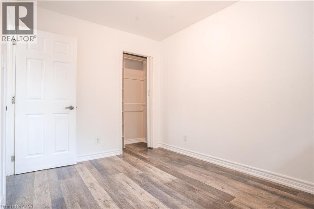 Bright, freshly painted bedroom featuring wood-finish flooring, two closets with six-panel doors, and clean white walls throughout - 695 Glen Forrest Boulevard Unit# Upper, Waterloo, ON - Indoor Photo Showing Other Room