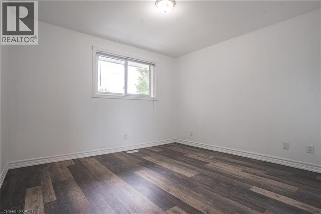Bright, light-filled bedroom featuring newly installed wood-finish flooring, clean white walls, and a recessed ceiling light - 695 Glen Forrest Boulevard Unit# Upper, Waterloo, ON - Indoor Photo Showing Other Room