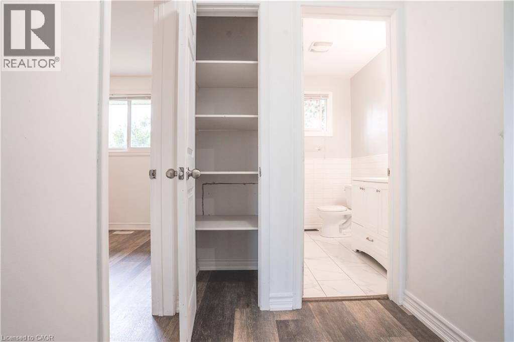 Hallway featuring abundant built-in storage with multiple shelves, wood-finish flooring, and bright natural lighting from nearby windows - 695 Glen Forrest Boulevard Unit# Upper, Waterloo, ON - Indoor Photo Showing Other Room