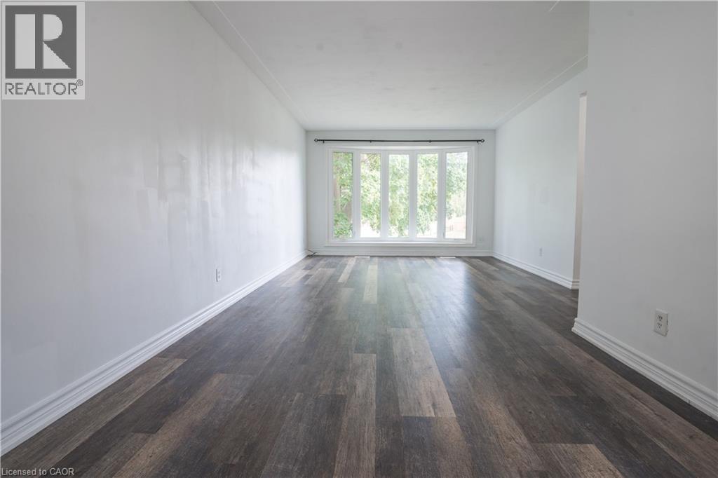 Expansive interior featuring wood-finish flooring, white walls, and a large multi-pane window - 695 Glen Forrest Boulevard Unit# Upper, Waterloo, ON - Indoor Photo Showing Other Room