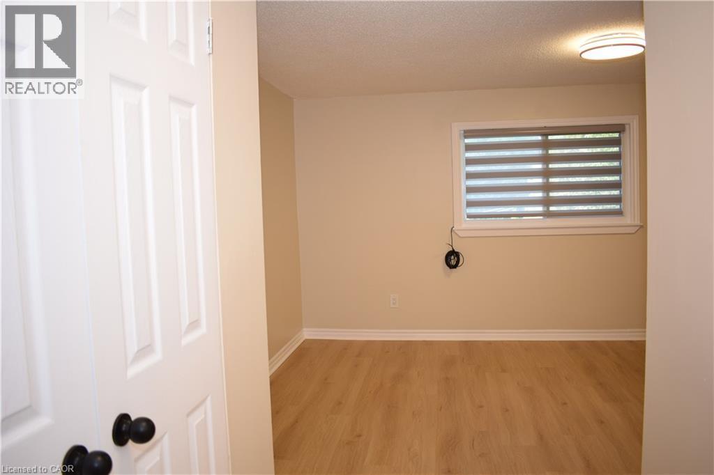 Wood-finish flooring with white baseboards, a window with horizontal blinds, and a flush-mount ceiling light fixture - 655 Albert Street Unit# A, Waterloo, ON - Indoor Photo Showing Other Room
