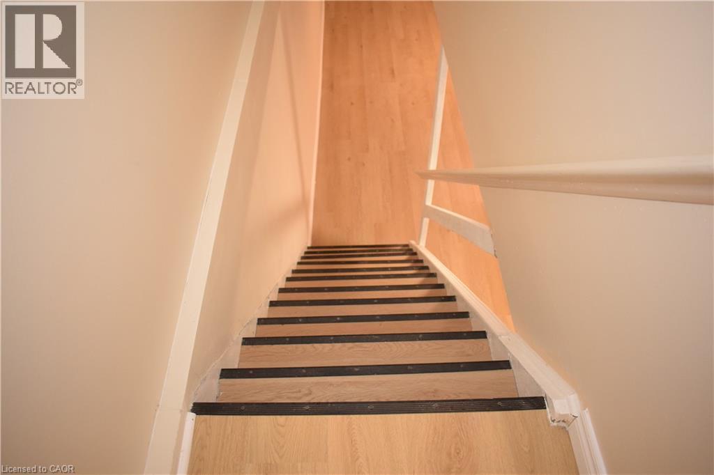 Staircase featuring wood-finish treads with dark risers, a white painted handrail, and light-toned wall finishes - 655 Albert Street Unit# A, Waterloo, ON - Indoor Photo Showing Other Room