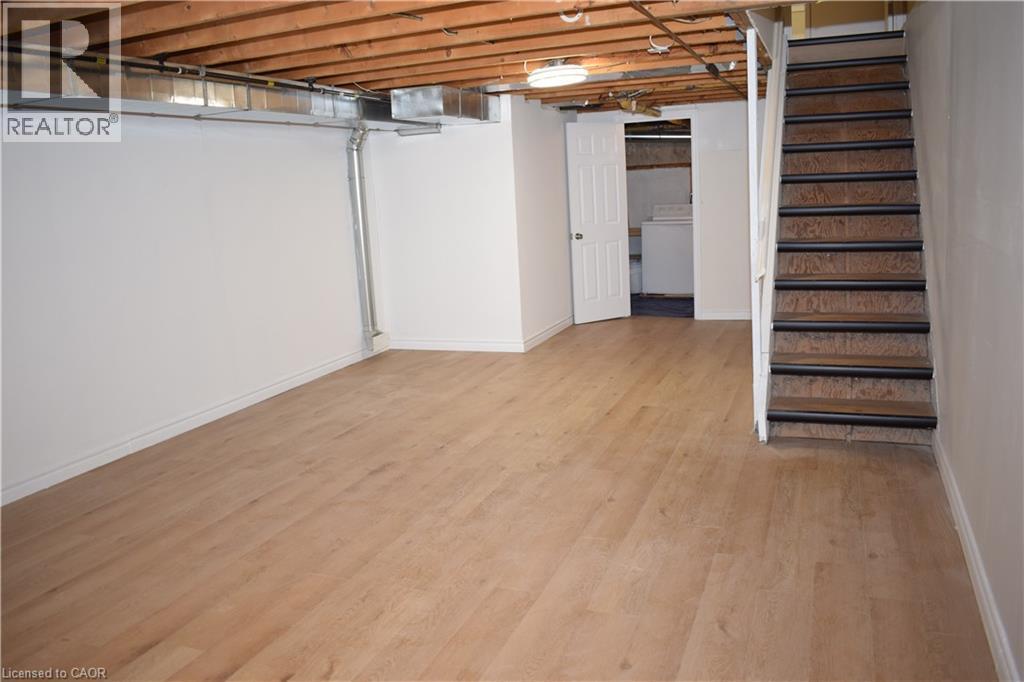 Finished lower level with wood-finish flooring, white painted walls, and an exposed wood beam ceiling - 655 Albert Street Unit# A, Waterloo, ON - Indoor Photo Showing Basement