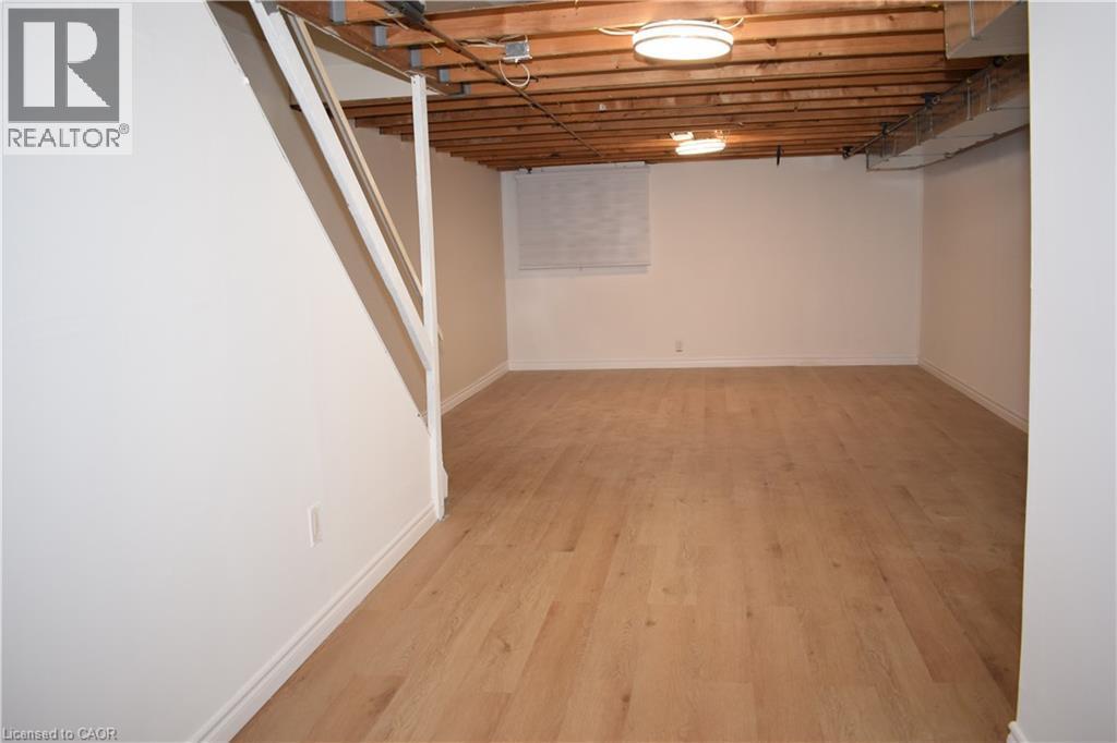 Spacious room featuring wood-finish flooring, white painted walls, and overhead lighting - 655 Albert Street Unit# A, Waterloo, ON - Indoor Photo Showing Other Room