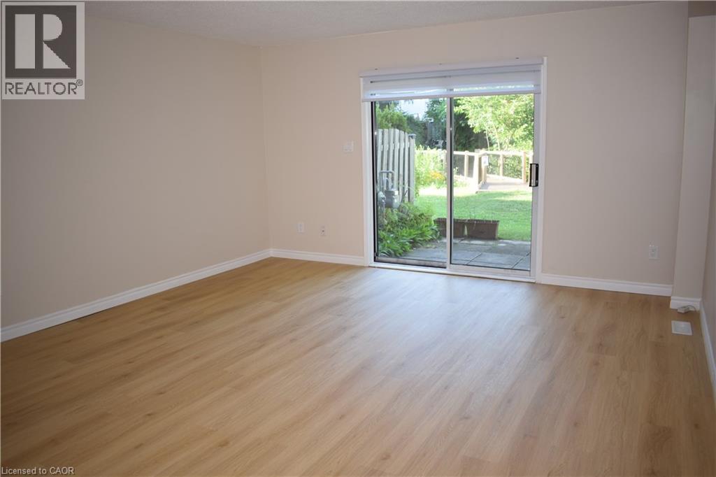 Light-tone wood-finish flooring, neutral wall tones, sliding glass door, and backyard patio - 655 Albert Street Unit# A, Waterloo, ON - Indoor Photo Showing Other Room
