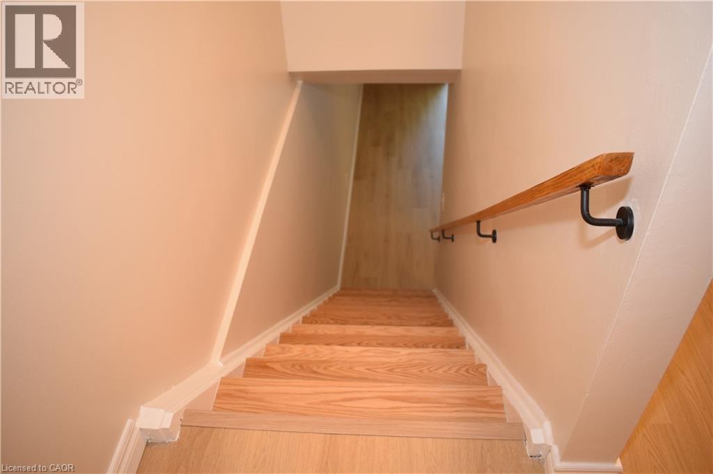 Staircase with wood-finish steps and a wooden handrail with black mounts - 655 Albert Street Unit# A, Waterloo, ON - Indoor Photo Showing Other Room