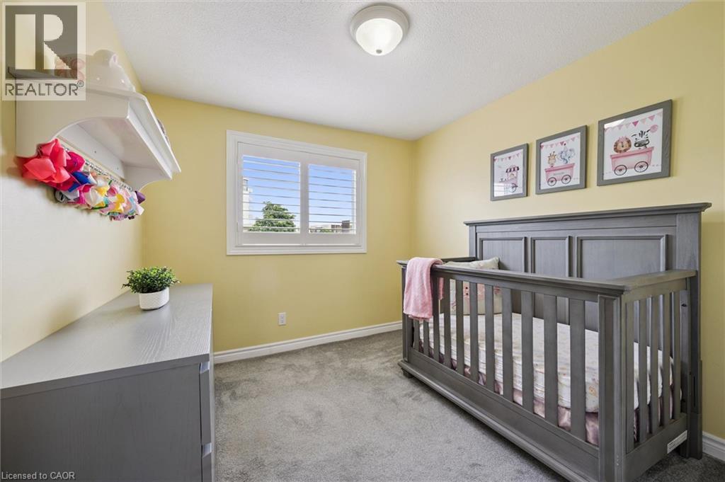 Wall-to-wall carpeting, window with plantation shutters, ceiling-mounted light fixture, and painted walls - 60 Elmsdale Drive Unit# 25, Kitchener, ON - Indoor Photo Showing Bedroom
